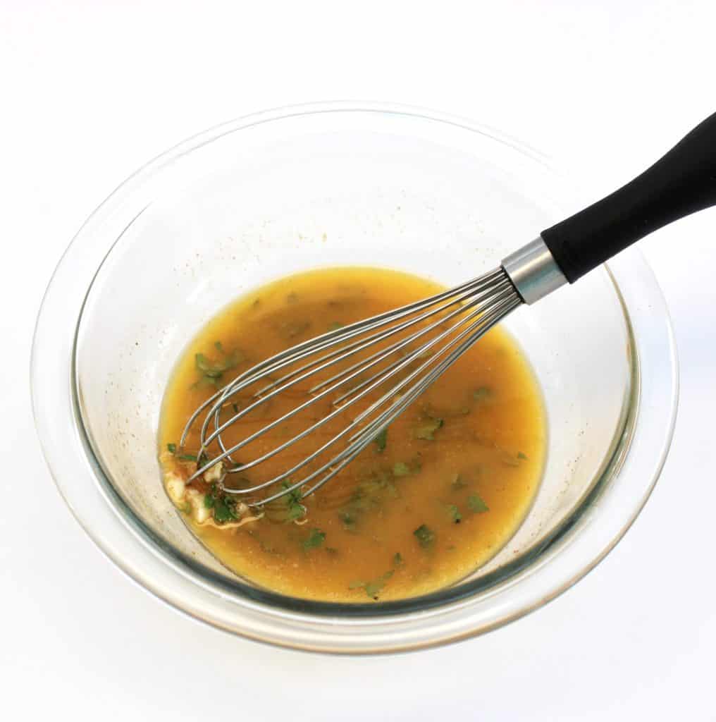 garlic butter sauce in glass bowl with whisk