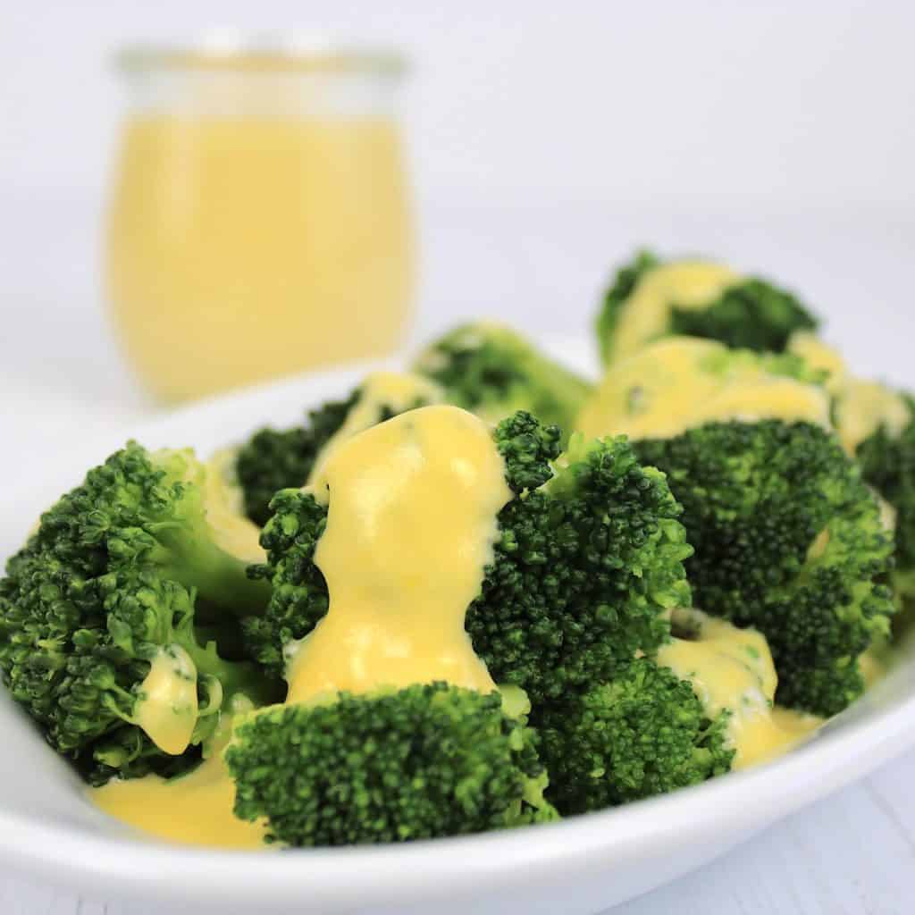 cheese sauce over broccoli on white plate