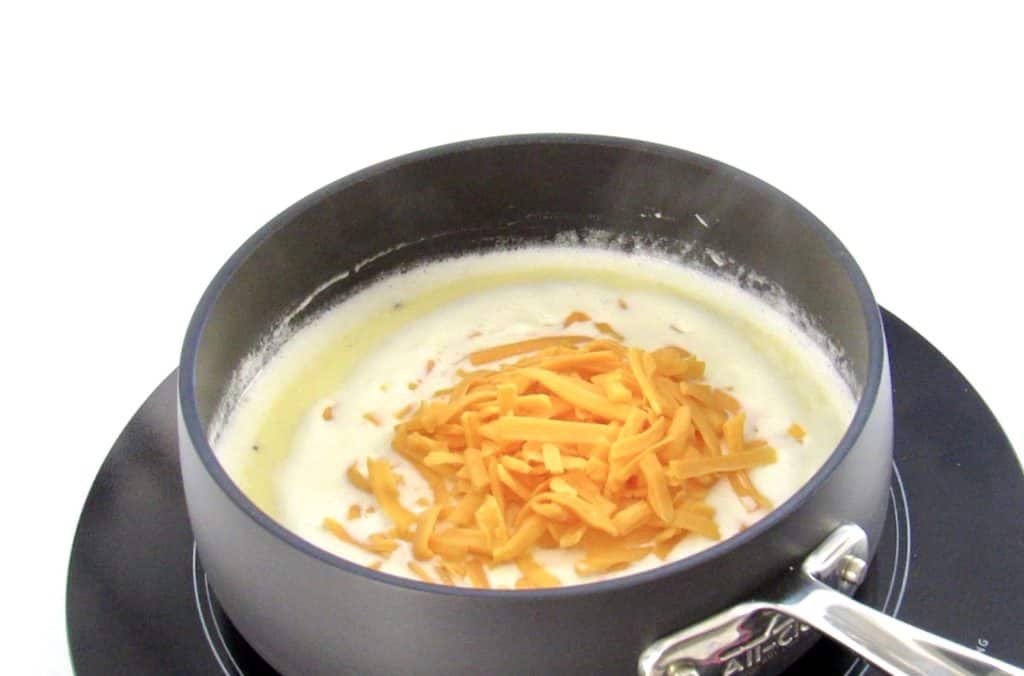 shredded cheese in heavy cream in a pan