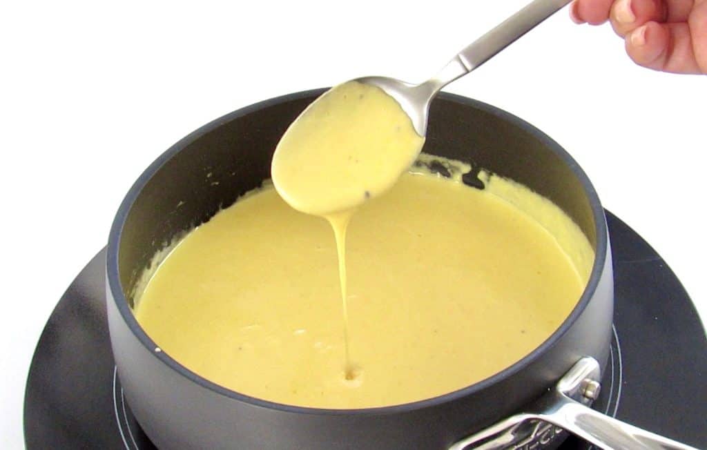 cheese sauce being spooned out of pan