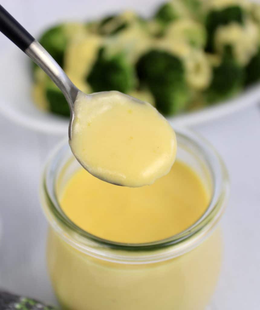 cheese sauce being spooned out of glass jar