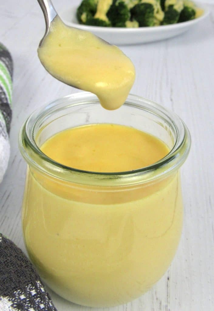 cheese sauce being spooned out of glass jar