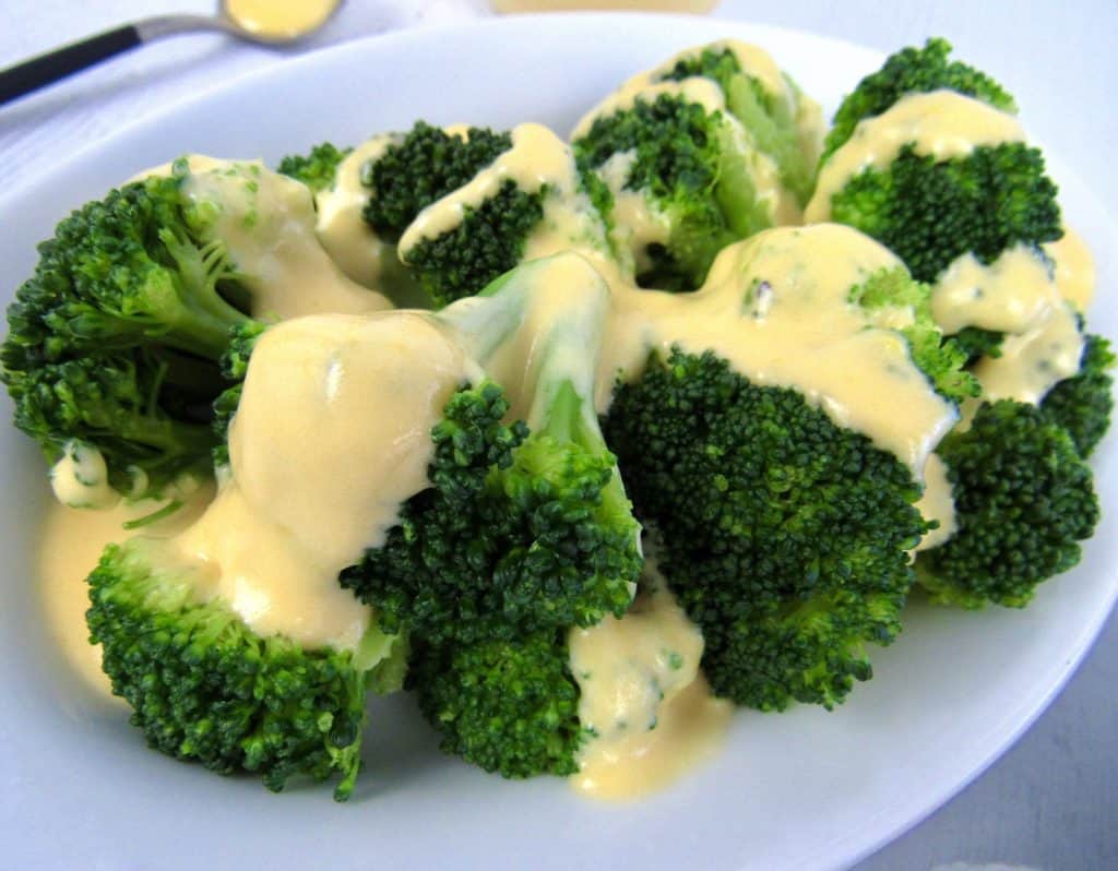 cheese sauce over broccoli on white plate