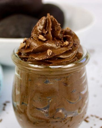 avocado chocolate mousse in glass jar with avocados in background