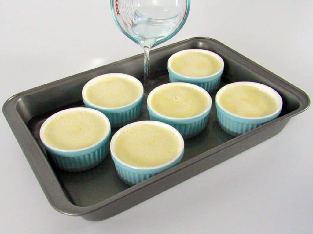 water being poured into baking pan with ramekins