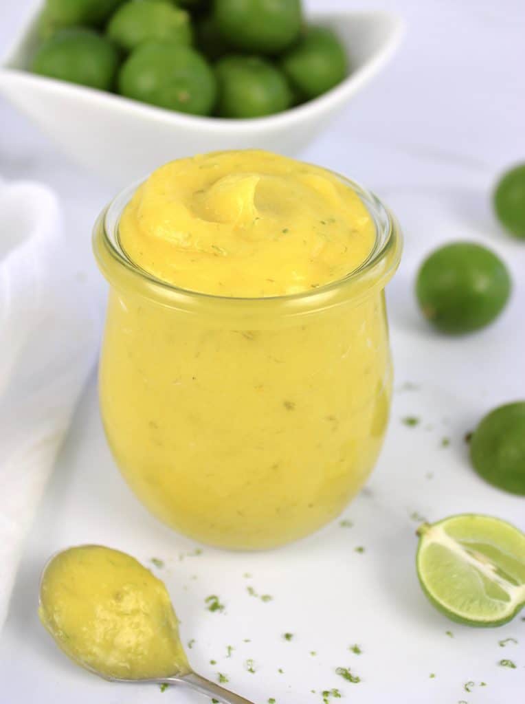 Keto Key Lime Curd in glass jar with limes in background