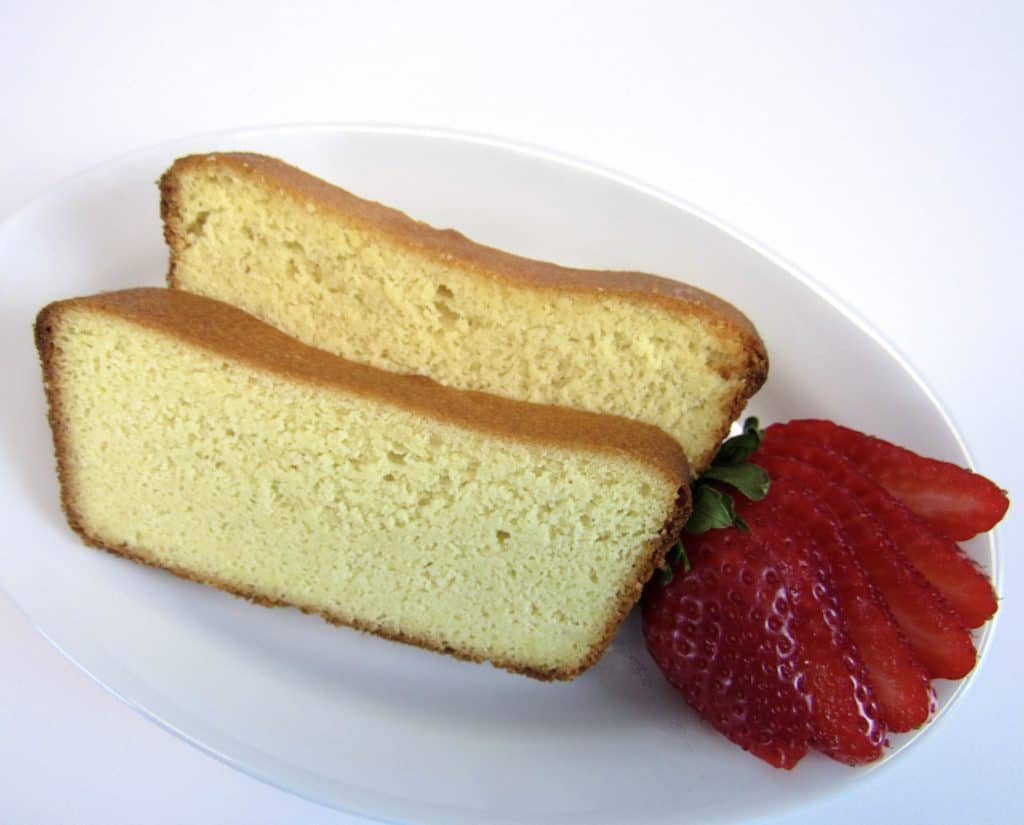 sliced pound cake on white plate with strawberry on side