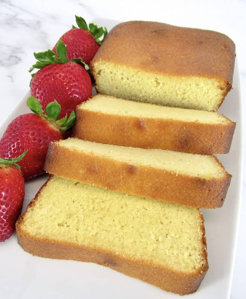 sliced pound cake on white plate with strawberries on side