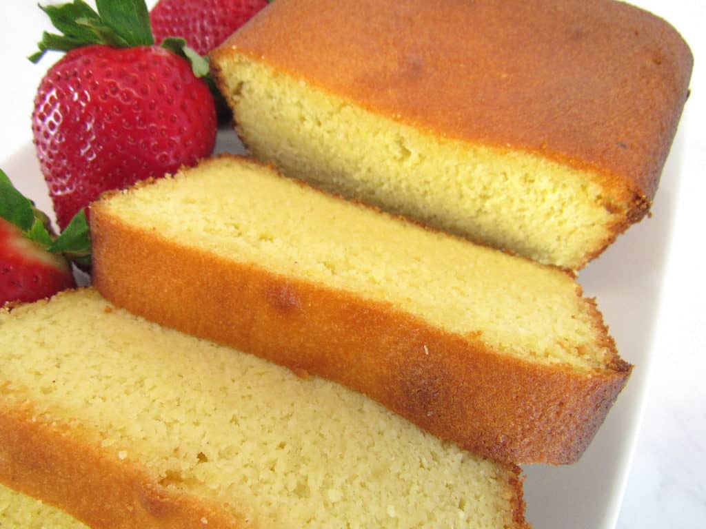 sliced pound cake on white plate with strawberries on side