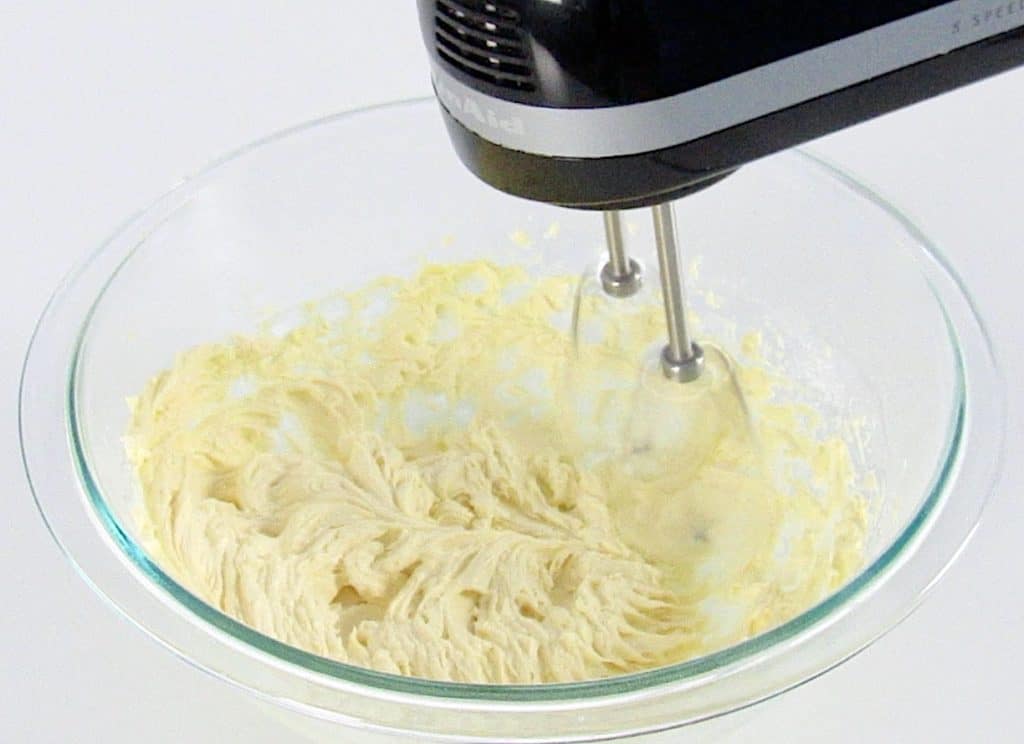 butter and sugar being whipped in glass bowl