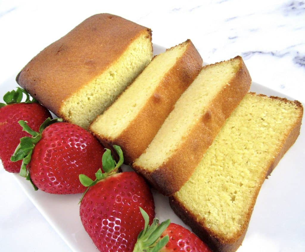 sliced pound cake on white plate with strawberries on side