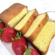 sliced pound cake on white plate with strawberries on side
