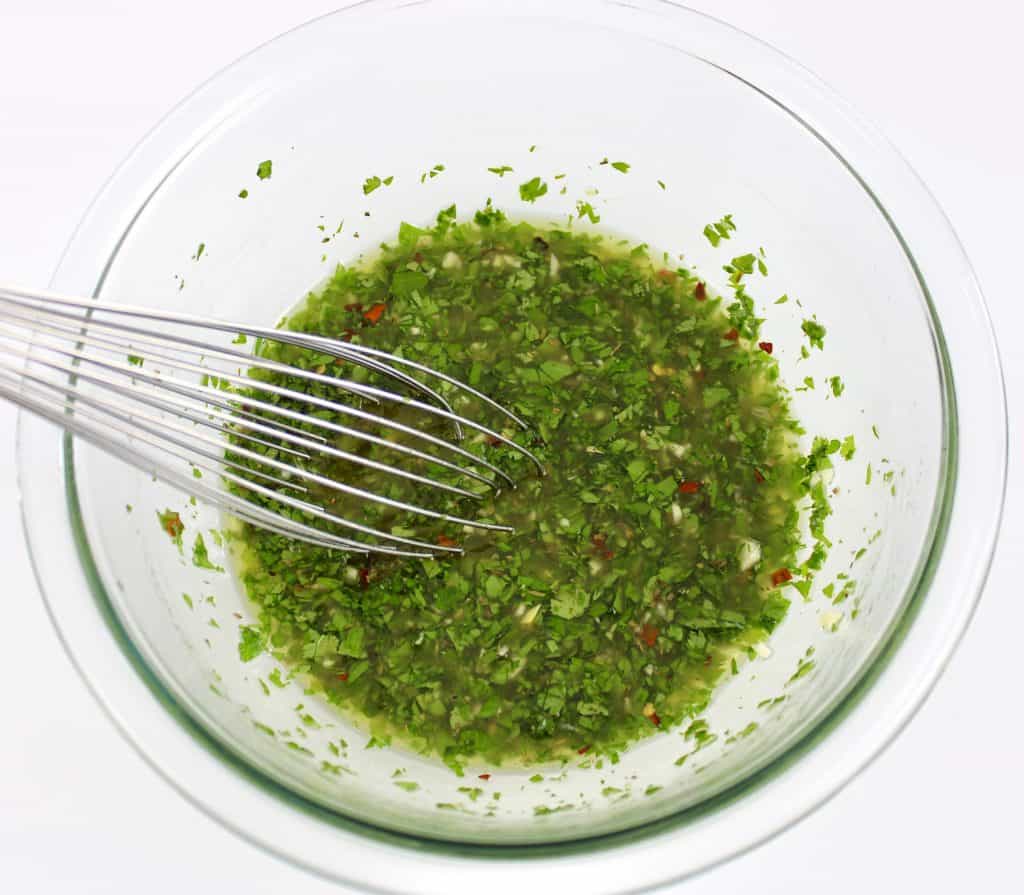 chimichurri sauce being whisked in glass bowl