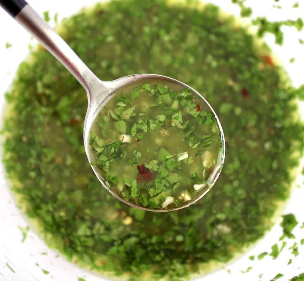 chimichurri sauce being spooned out of glass bowl