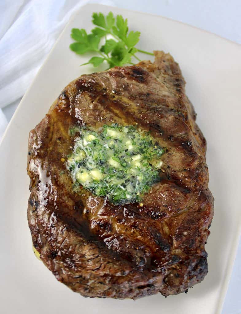 grilled ribeye steak with partially melted compound butter on top
