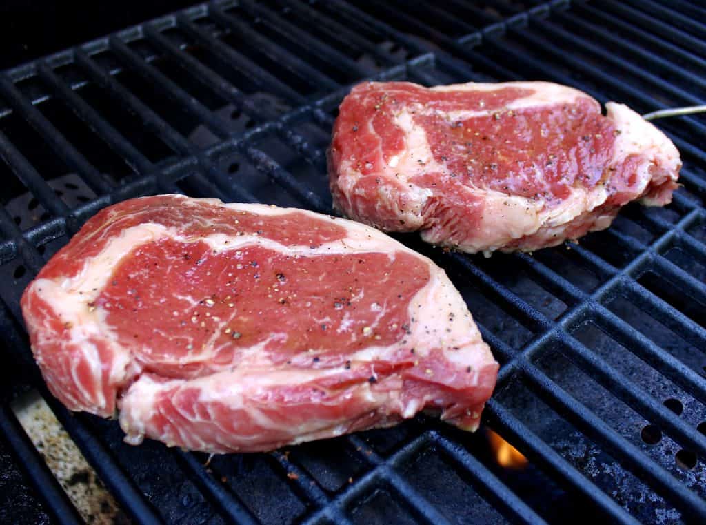 two ribeye steaks on grill