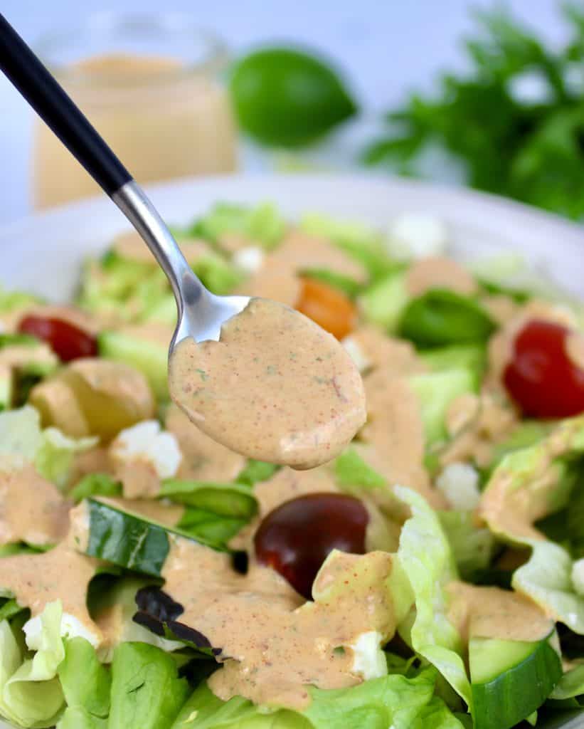 salad with chipotle ranch being spooned over the top