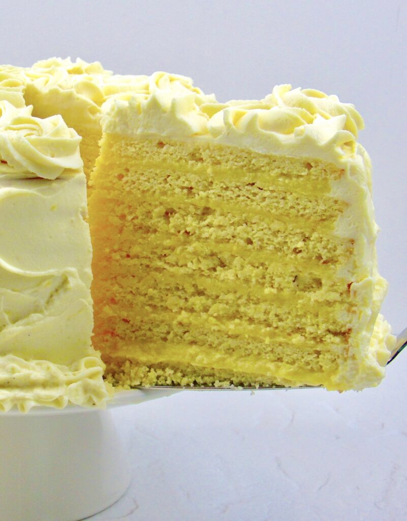 lemon curd cake slice being removed from cake on white cake stand