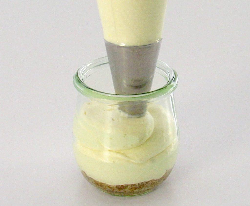 cheesecake filling being piped into glass jar