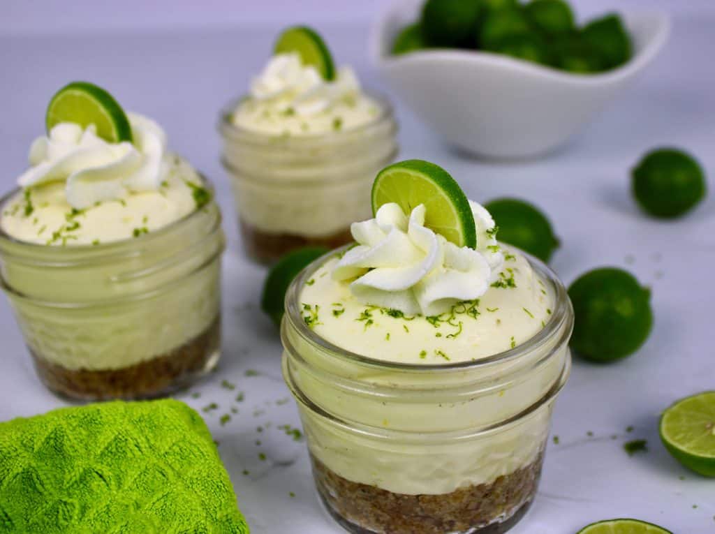Keto No Bake Key Lime Cheesecake in 3 glass jars with whip cream and lime on top