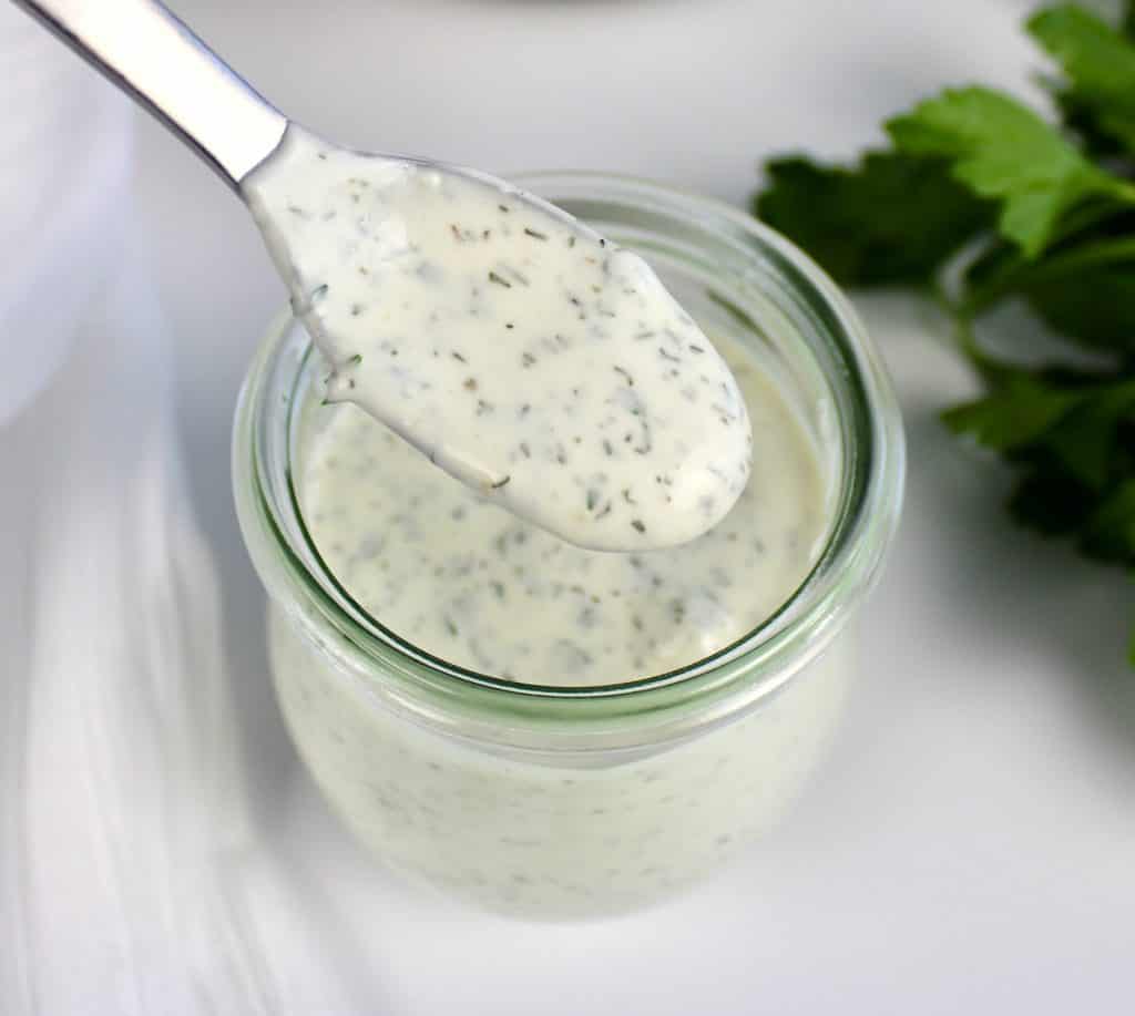 ranch dressing being spooned out of glass jar