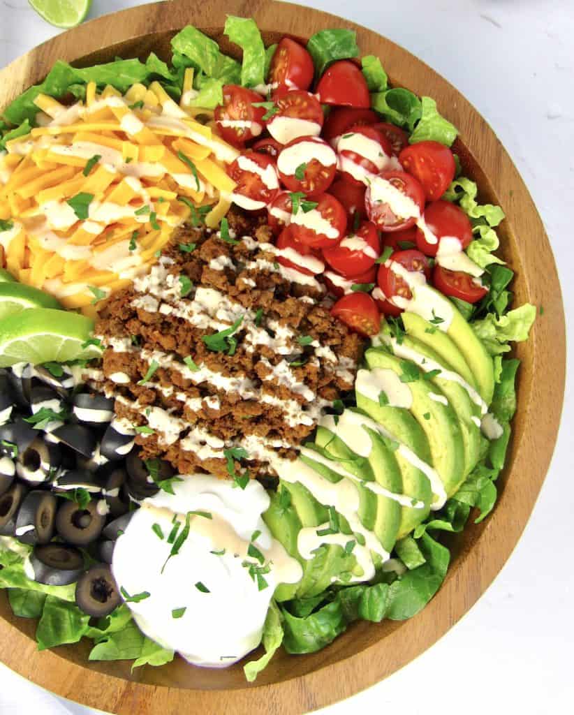 overhead view of Keto Taco Salad in wooden bowl with dressing drizzled on top