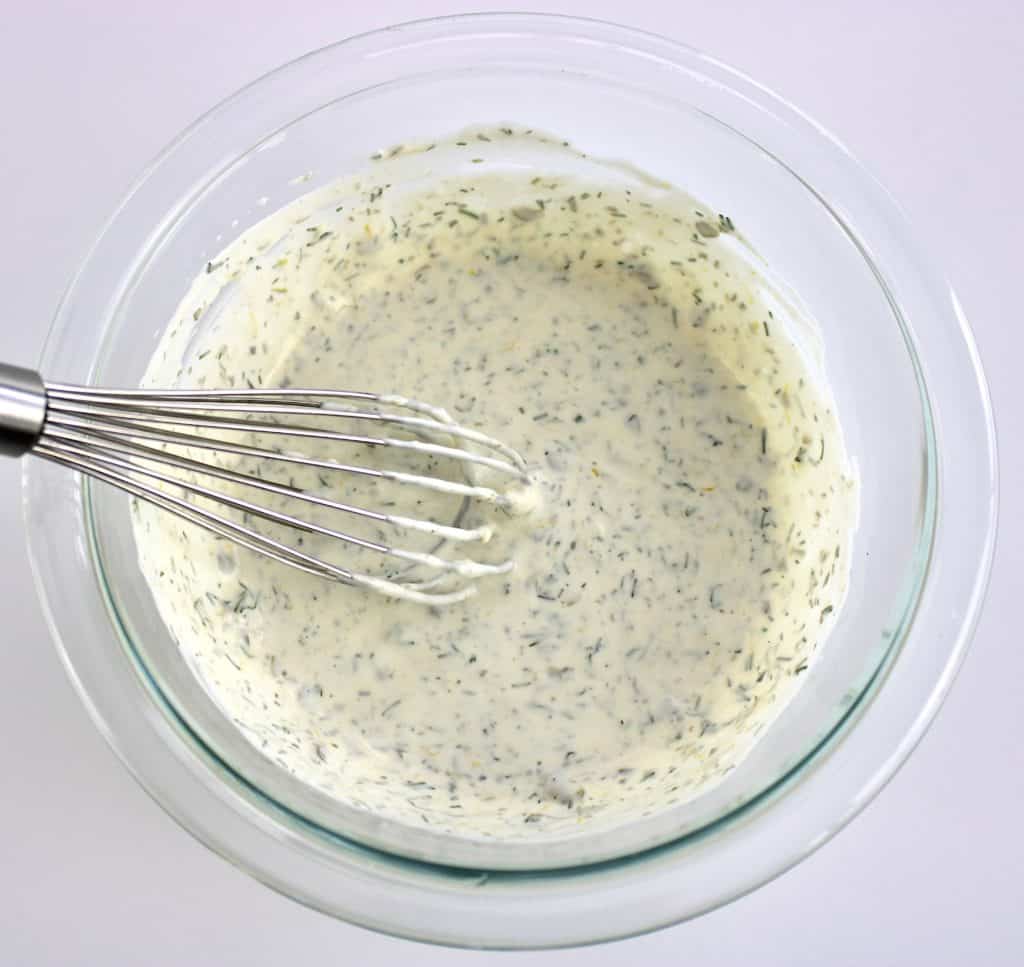 creamy dill sauce ingredients in glass bowl with whisk