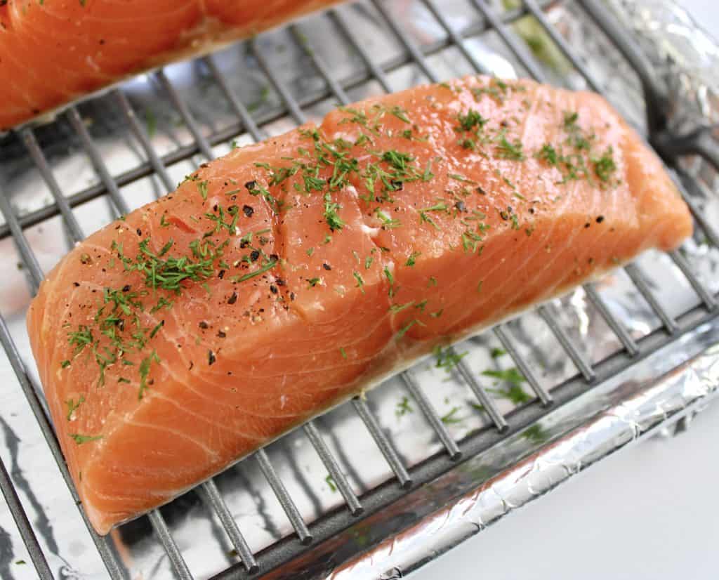 raw salmon slice on baking rack with dill on top