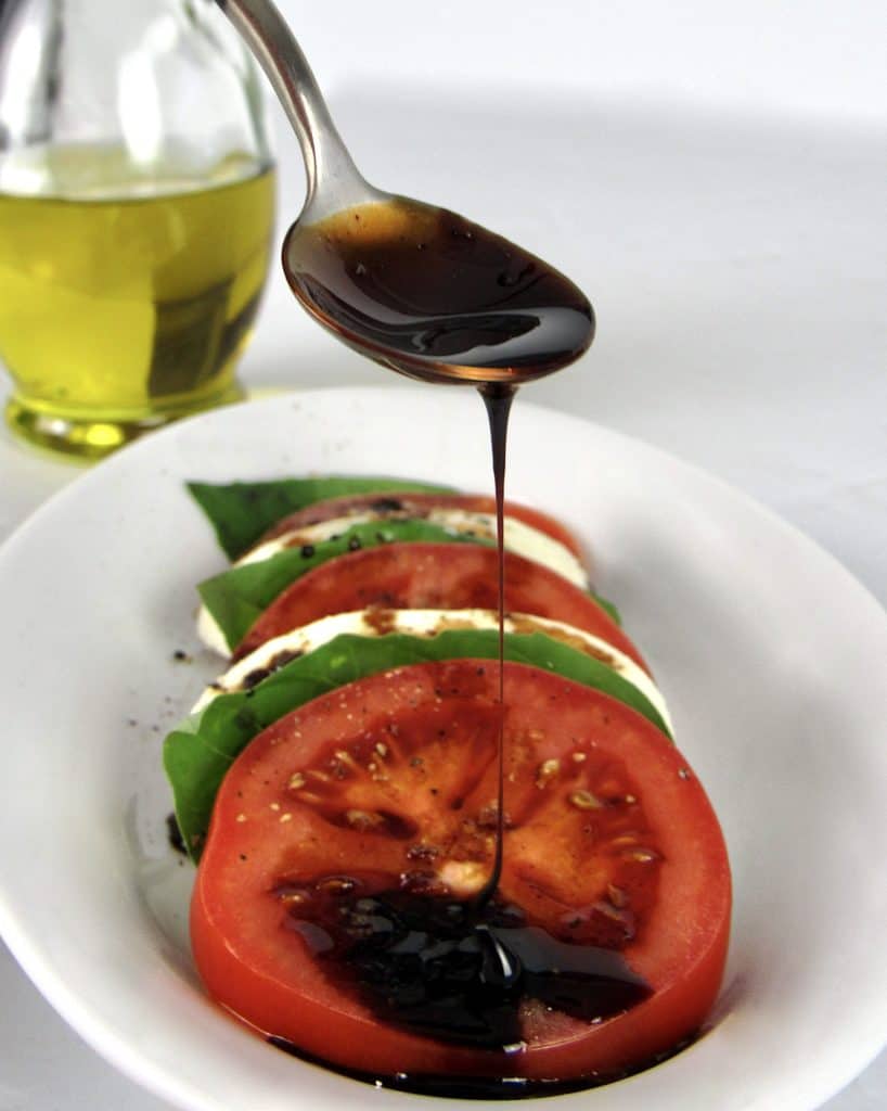 Balsamic Reduction being drizzled over a tomato with spoon