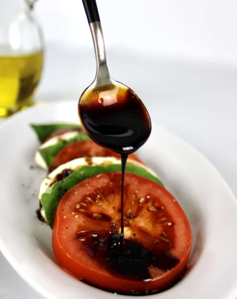 Balsamic Reduction being drizzled on tomato from a spoon