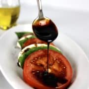 Balsamic Reduction being drizzled on tomato from a spoon
