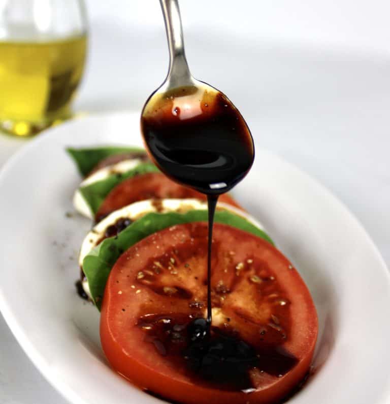 Balsamic Reduction being drizzled on tomato from a spoon