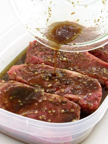 marinade being poured over 4 steaks in tupperware container