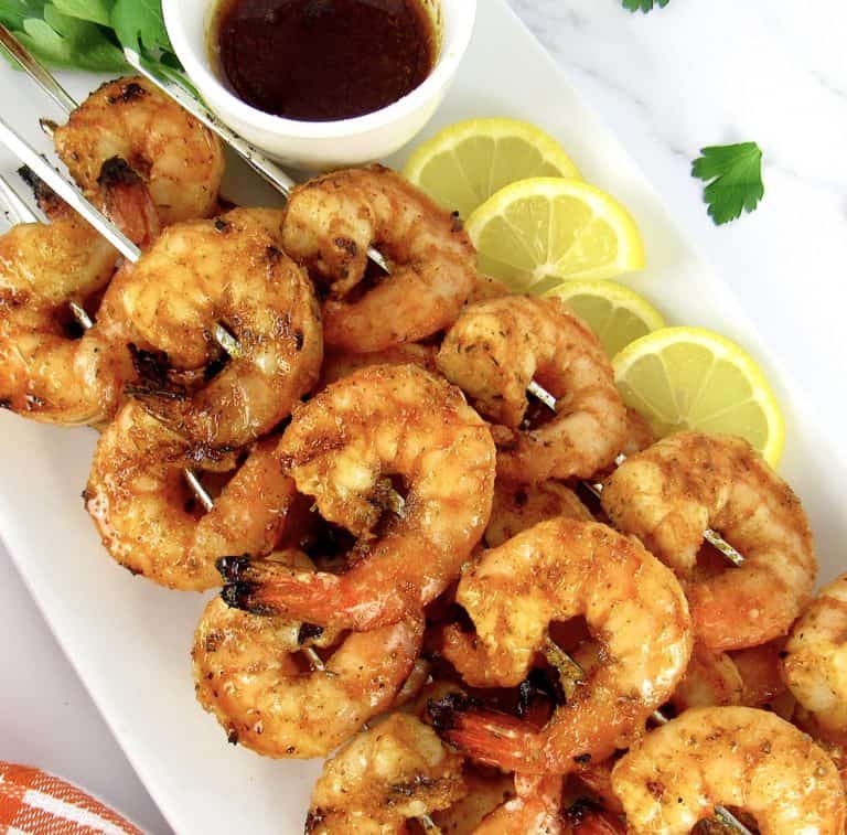 Grilled Cajun Shrimp on white plate with cajun butter on side