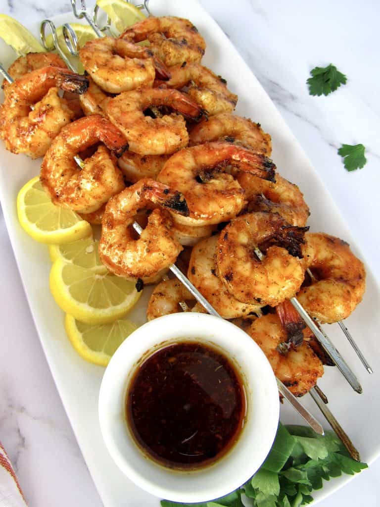Grilled Cajun Shrimp on white plate with cajun butter on side