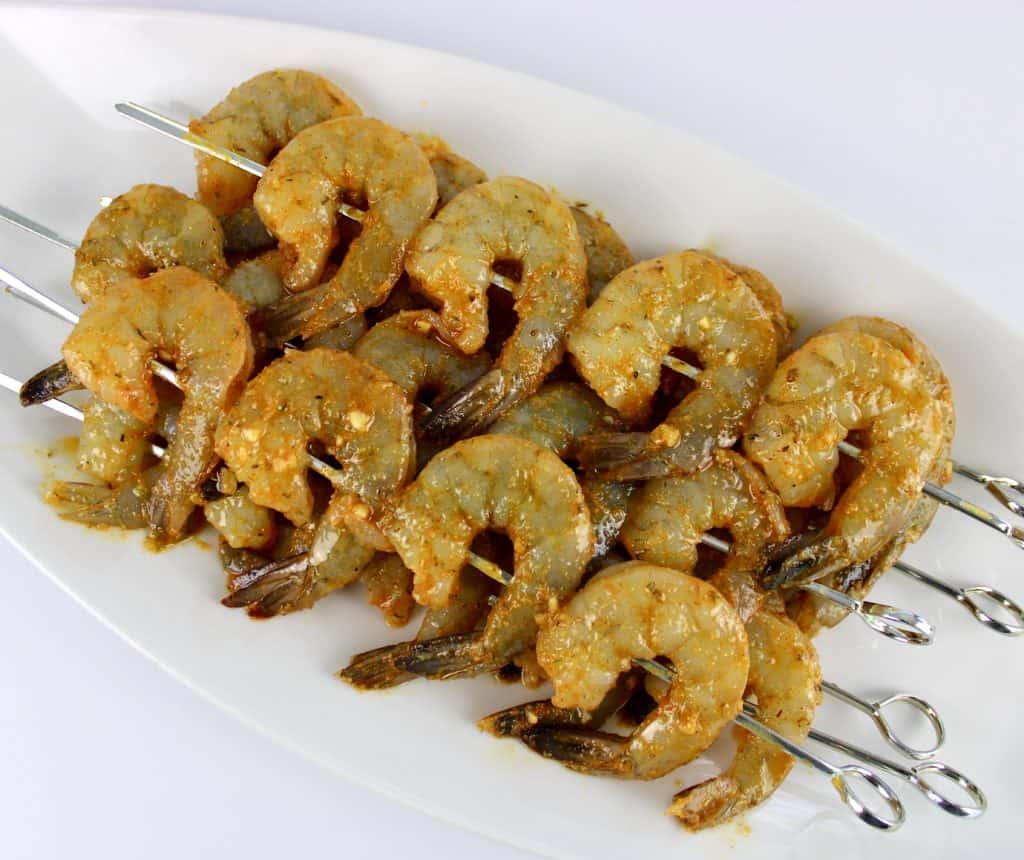 raw shrimp on skewers with cajun sauce on top