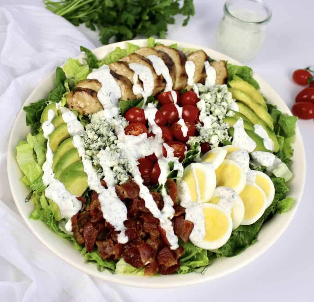 cobb salad with grilled chicken and ranch dressing drizzled on top