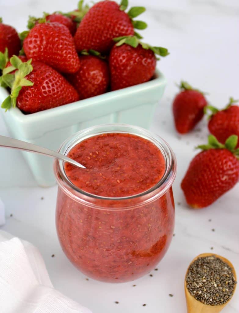 Strawberry Chia Seed Jam in jar with strawberries in background