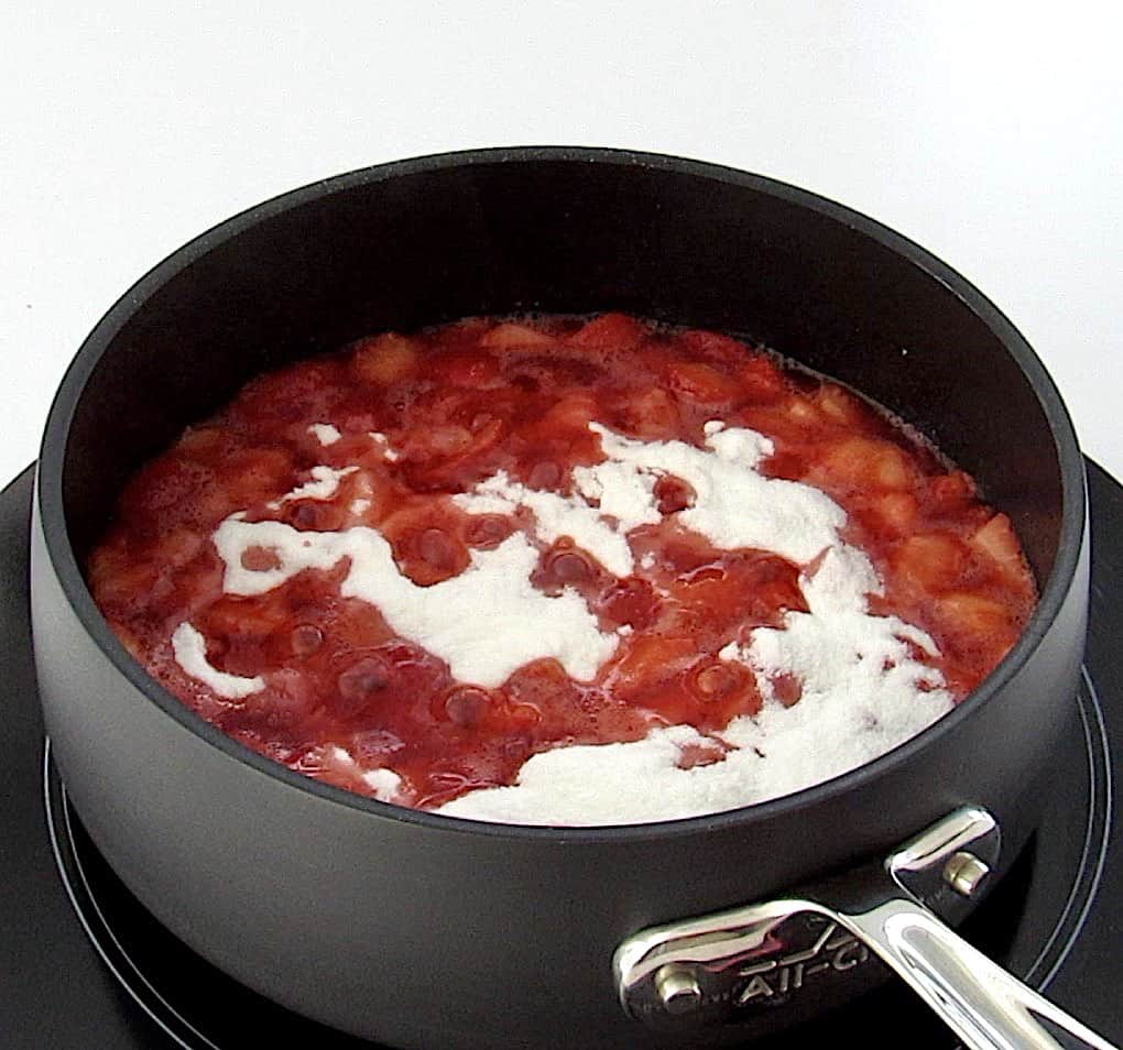 chopped strawberries in saucepan with sweetener on top