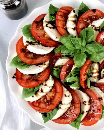 Caprese Salad in concentric circles with Balsamic Reduction drizzled on top and fresh basil in ceter