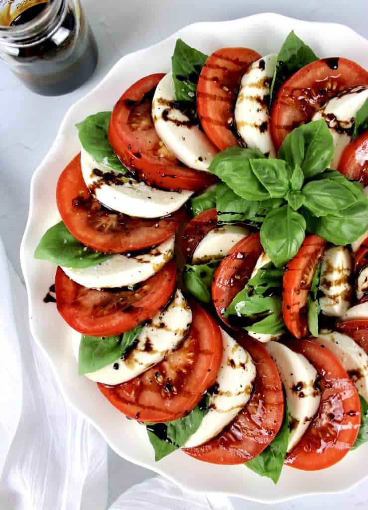 Caprese Salad in concentric circles with Balsamic Reduction drizzled on top and fresh basil in ceter