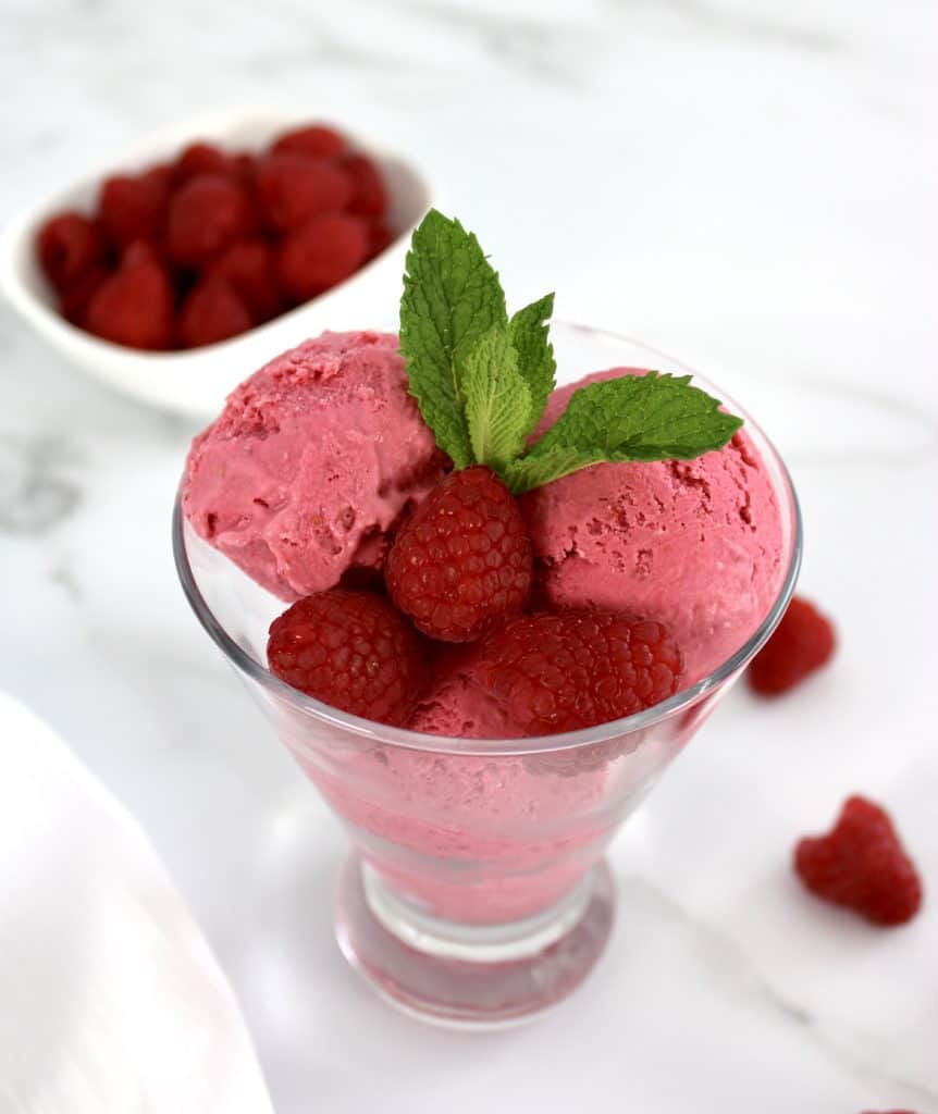 raspberry ice cream in glass with mint sprig