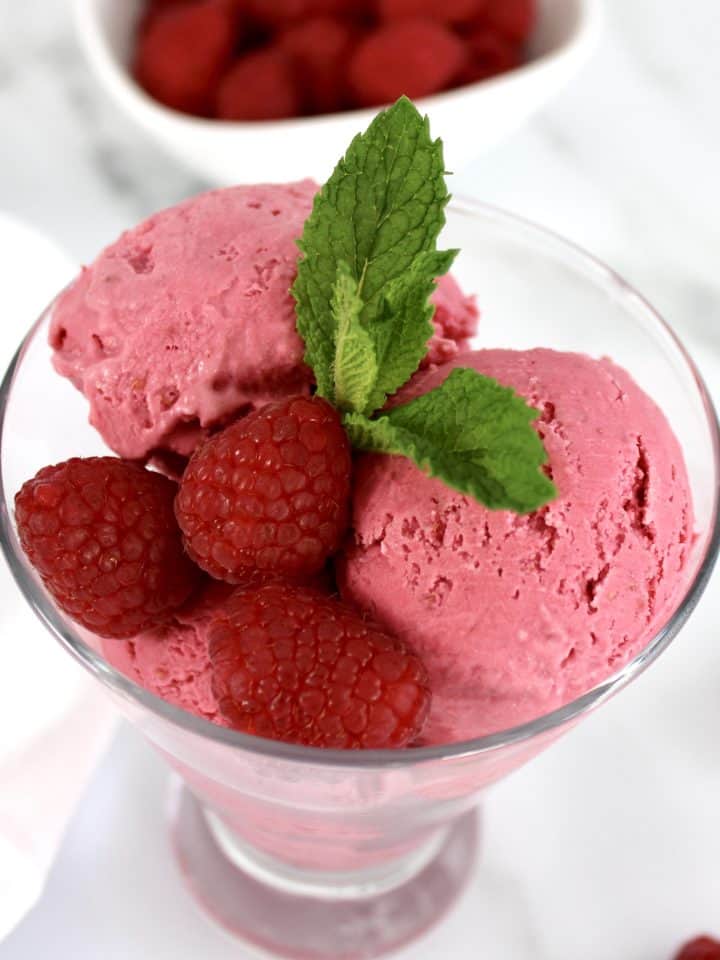 closeup of raspberry ice cream in glass with mint sprig
