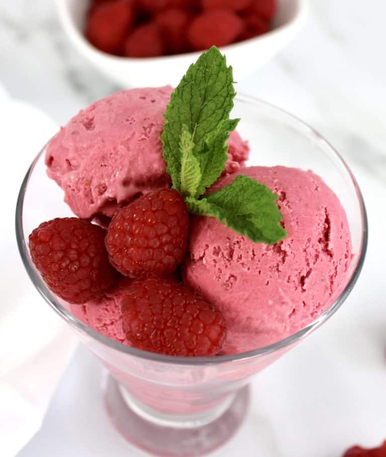 closeup of raspberry ice cream in glass with mint sprig