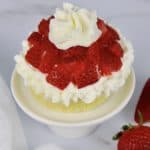 mug cake with whip cream and chopped strawberries on top
