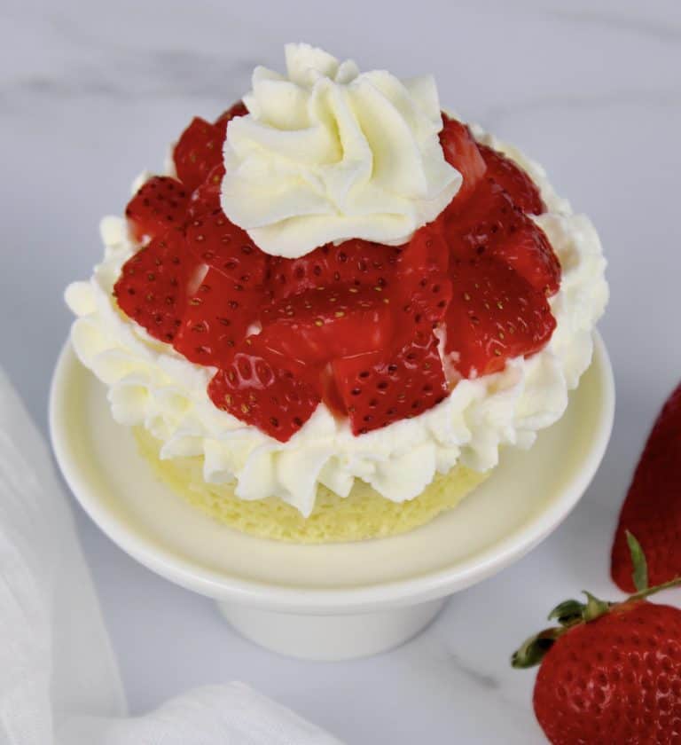 mug cake with whip cream and chopped strawberries on top