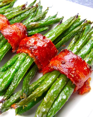 bacon wrapped green beans on white plate running caddy corner