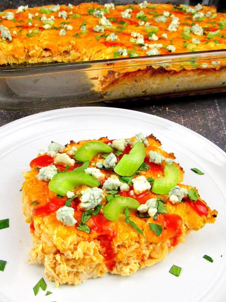 slice of buffalo chicken casserole on white plate with casserole in background