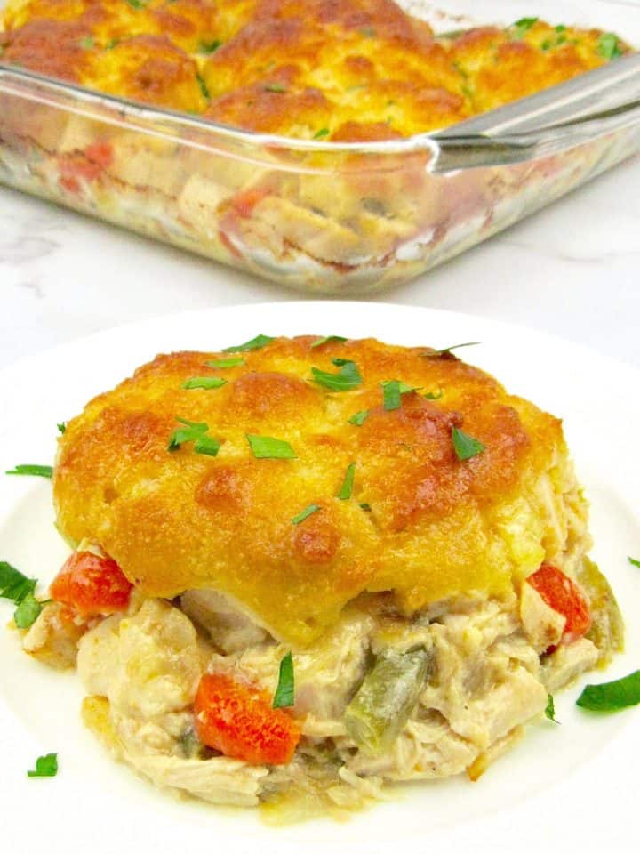 piece of chicken pot pie casserole on white plate with casserole in the background