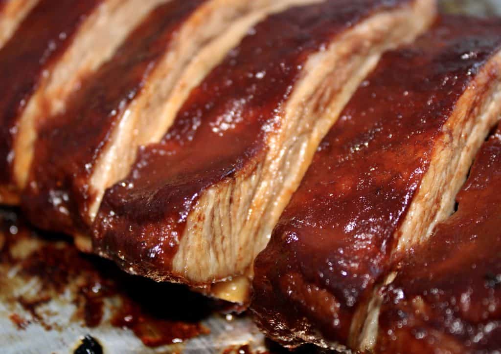 closeup of cut bbq ribs on baking sheet